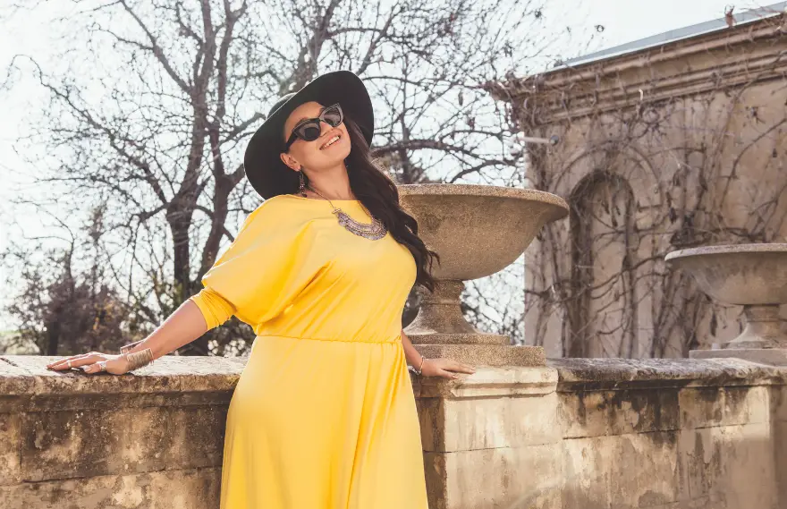 A woman in a yellow maxi dress and big black hat